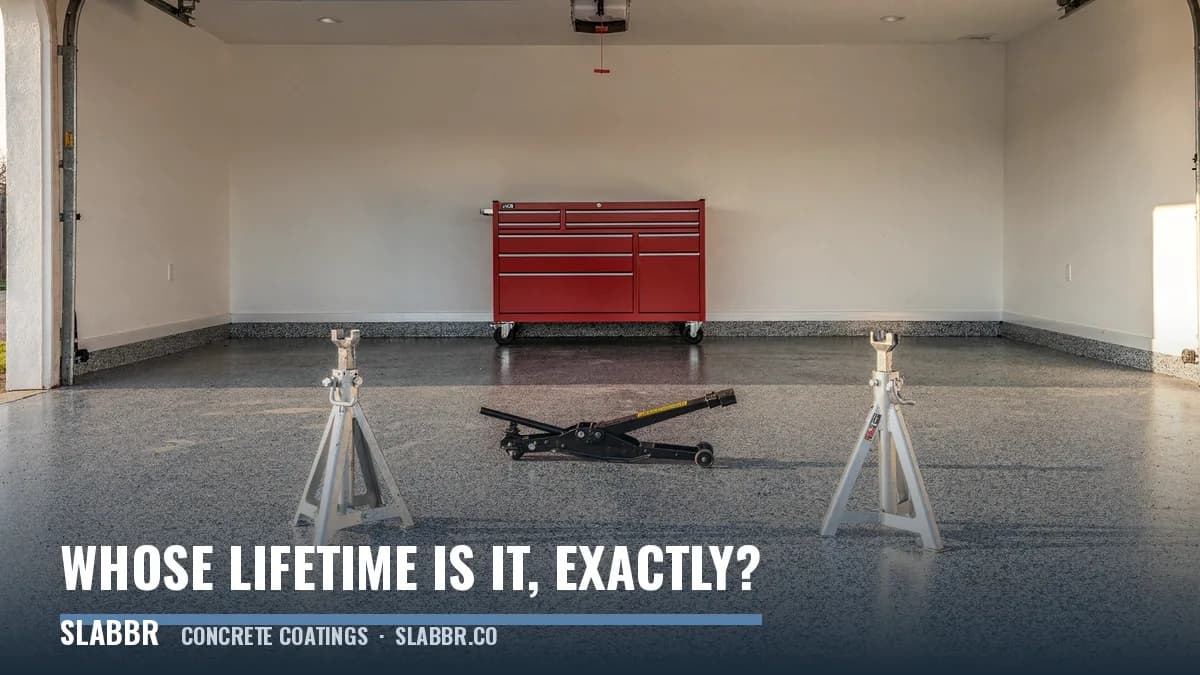 A gray flake coated garage floor still intact after years of use, with a rolling tool chest and jack stands set on it